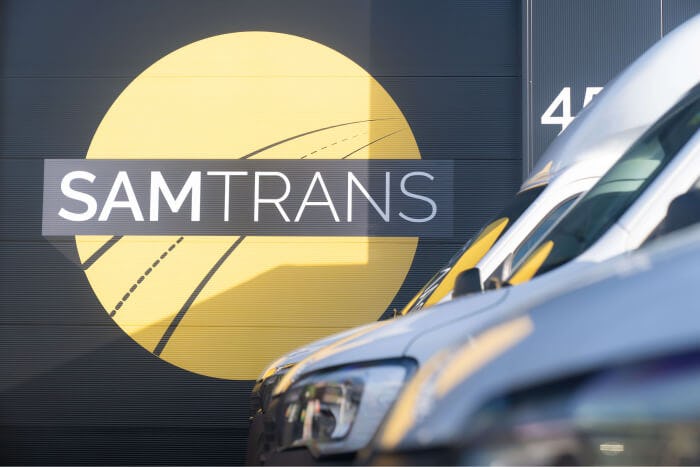 Wagens van  Express dienst SamTrans geparkeerd bij loods met logo.